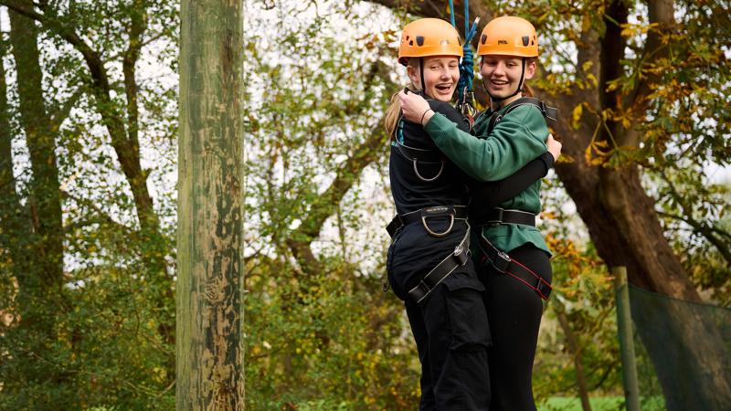 two-girls-doing-a-crate-stacking-activity-holding-onto-each-other-and-laughingmin